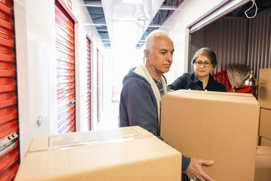 Senior couple moving boxes in storage facility