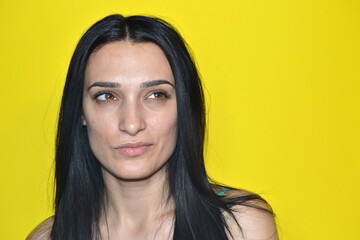 Happy woman thinking and standing isolated on yellow background