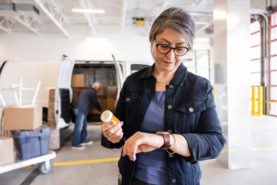 Senior woman with prescription checking wristwatch at storage facility