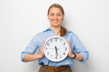 Portrait of happy young woman in casual clothes holding clock, standing over white background