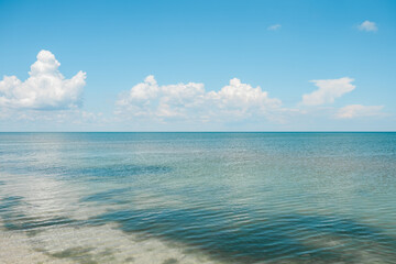 Seashone scene blue sea sky white clouds. Hot summer clear day