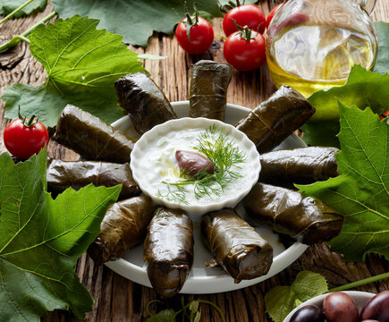 Traditional dish, dolmades made of stuffed grape leaves served with yoghurt tzatziki sauce on a wooden table