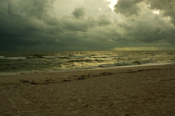 Thick heavy storm clouds fill the sky over the gulf of Mexico in bonita springs, Florida, as waves crash on the beach.
