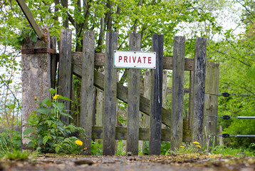 Private sign on a wooden gate in front of way in nature