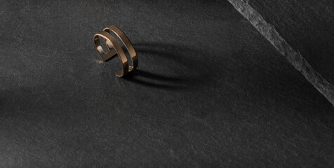 Double shape modern golden ring on dark stone surface with copy space