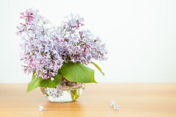 Bouquet of lilac flowers in glass vase on white background, beautiful card with copy space	