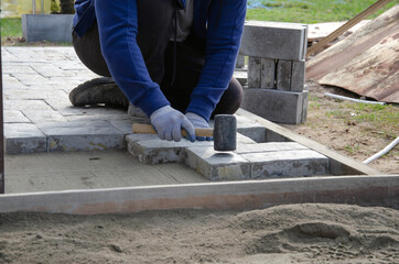 Construction of pavement near the house. Bricklayer places concrete paving stone blocks for building up a Sidewalk pavement