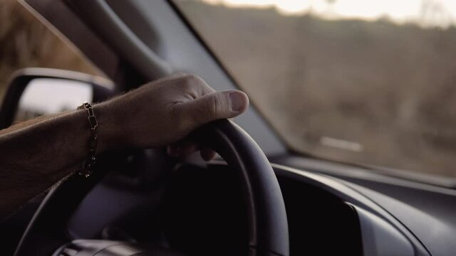Man hands on steering wheel of car driving, slow motion image.