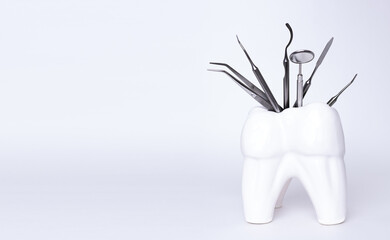 Dental professional steel tools in tooth shaped holder on grey background. Set of metal medical equipment tools for teeth dental care. sickle probe, dental explorer, mirror, burnisher, forceps