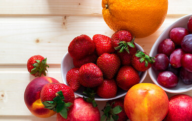 Health and life benefits of strawberries, grapes, nectarines, oranges; high angle photo of fruit on traditional wooden background