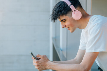 teenage boy with mobile phone and headphones on the balcony