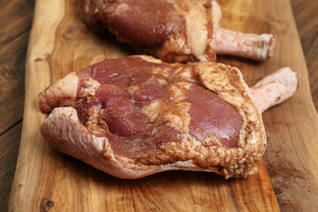 Two fresh uncooked duck legs on a wooden cutting board and wooden table. Poultry product.