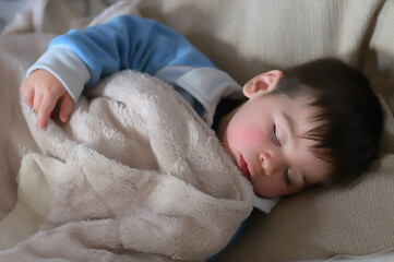 bambino che dorme beato tra le coperte