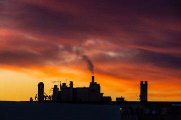 Silhouette de toit et de fum&eacute;e de chemin&eacute;e devant un couch&eacute; de soleil