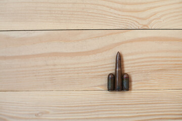 Three different caliber bullets together on a wooden background. Bullets on a wooden background. Military concept.