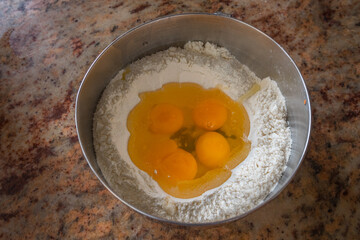 Flour and eggs in a metal bowl. Ready to be mixed for a delicious recipe.