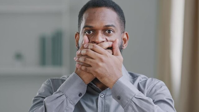 African American bearded black male millennial businessman lawyer or student crime witness closing covers his mouth with hands refusing to tell terrible secret, promises keep mystery silence, closeup