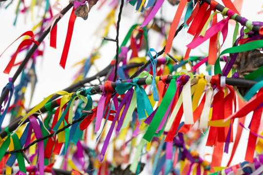 Wish Tree branches with colorful ribbons. Ritual tapes on wishing tree. Many multi-colored ribbons fluttering in the wind. Decorated maypole. Festival in the country. Sacral temple in the mountains