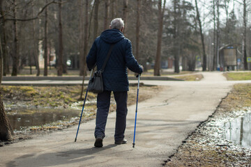 The man is walking Nordic walking. An elderly person maintains health by walking.