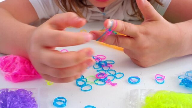 Young Creative Caucasian Girl Patiently Making a Colorful Bracelet Using Rubber Bands