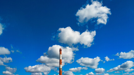 Boiler room chimney against a background of bright blue sky and white clouds