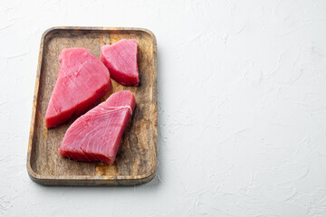 Obraz na płótnie Canvas Raw tuna steak, fresh red tuna fish fillet, on wooden tray, on white stone background , with copyspace and space for text