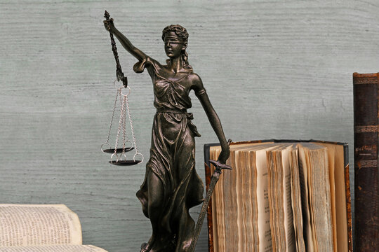 Justitia Figur und alte Bücher auf einem Holzuntergrund. Gerechtigkeit, Waage, Gericht