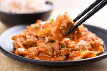 Stir-fried kimchi cabbage with pork eating with cooked rice by chopsticks, Homemade Korean food