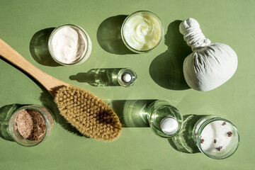 Body treatment and spa concept. Scrub, mask, cream and natural oil cosmetics on green background....