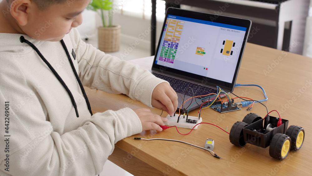 Wall mural young asia student remotely learn online at home in coding robot car and electronic board cable in s
