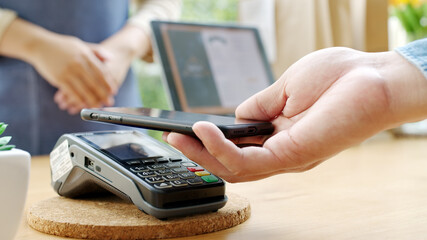 Close-up hand asia woman people work in small sme coffee cafe shop store owner use cashless wifi qr code nfc scan app smart pos reader sale in take out food drink order in urban city life contactless.