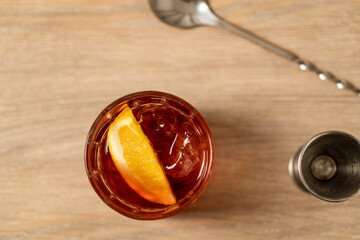 Top view of negroni cocktail with mixing spoon and jigger on wood surface