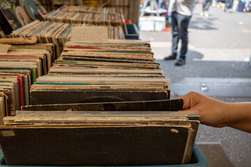 Selective focus at selected second hand old fashion phonograph discs  in the paper box at the stall...