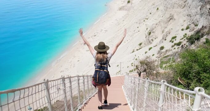 Traveler woman walking down new stairs at Egremni beach, Lefkada Greece.