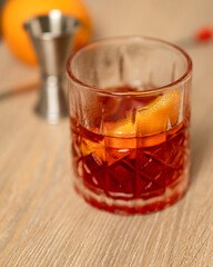 Close-up view of negroni cocktail with out-of-focus measuring cup and mixing spoon