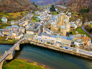 Obraz premium Aerial view of ancient castle of Chateau Estaing and medieval arched bridge across river Lot on background of Estaing cityscape in cloudy winter day, Aveyron, France..