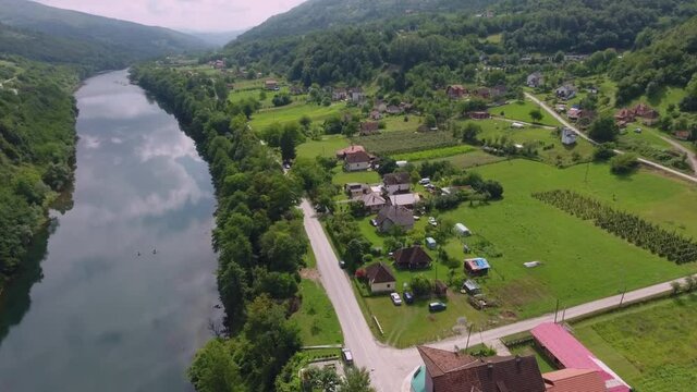 A drone flight over a scenic landscape view with an ancient graveyard and a river and main road that follows its course.