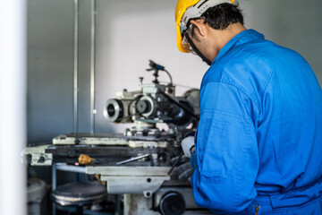 Asian mechanical worker male working on milling machine in factory.