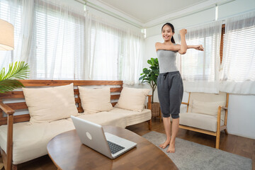 Asian young girl doing Yoga, follow online trainer in laptop at home.