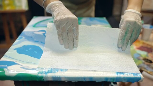 Woman artist is making acrylic paintings. Acrylic paint is spreading over the canvas. Artistic collaboration in workshop.