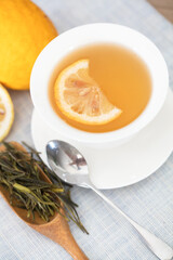 Bright tea soup with a slice of lemon and lemon fruit next to the tureen