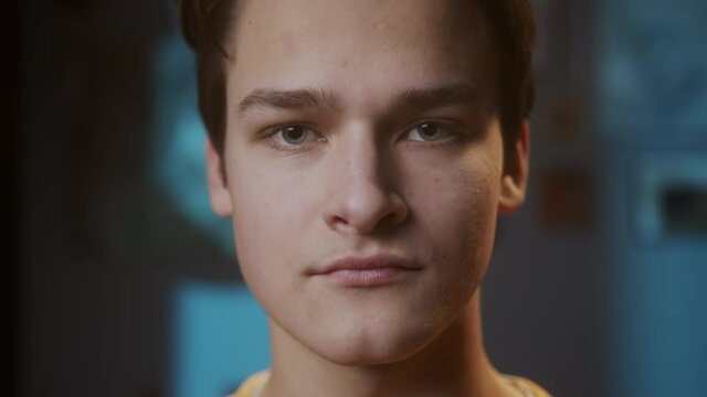 Portrait of young sad man with light blue eyes, looking in camera with joyless, sorrowful view. Close-up of male face student.