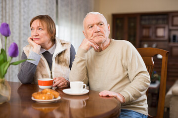 Upset elderly man sitting separately having problems in relationship with spouse..