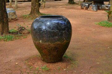 Old black water jar n the ground in the park