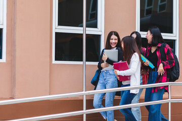 Group of four college student girls walking and talking together with intimate in front of school building. Learning and friendship of teens concept