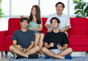 Four members Asian family consisting of parents, two adult sons spending time activity together,...