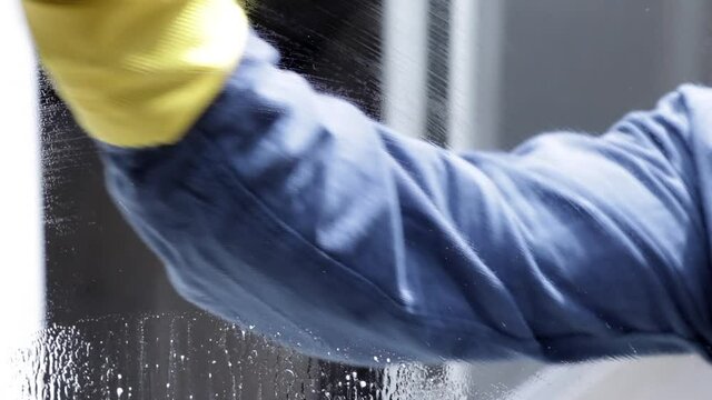 Close up de hombre con guantes de látex limpiando una ventana
