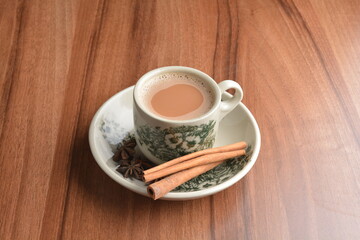 hot masala chai milk tea in traditional ceramic cup with cinnamon and star anise on wood table hot healthy asian beverage menu 