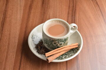 hot masala chai milk tea in traditional ceramic cup with cinnamon and star anise on wood table hot healthy asian beverage menu 