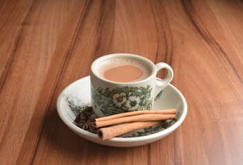 hot masala chai milk tea in traditional ceramic cup with cinnamon and star anise on wood table hot healthy asian beverage menu 